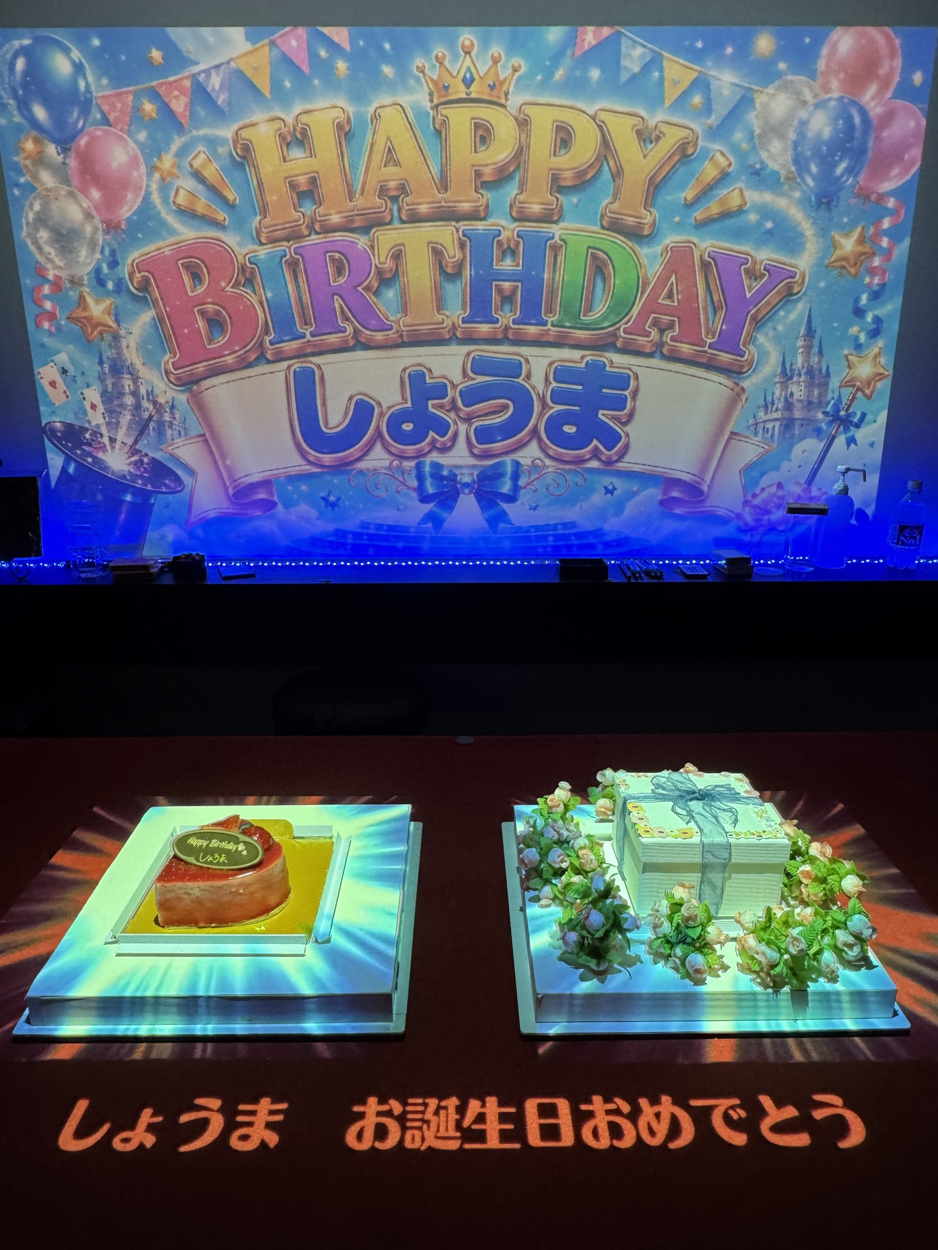 スクリーンとテーブルの映像でみのるくんとたかしくんを祝う大阪の誕生日サプライズ
