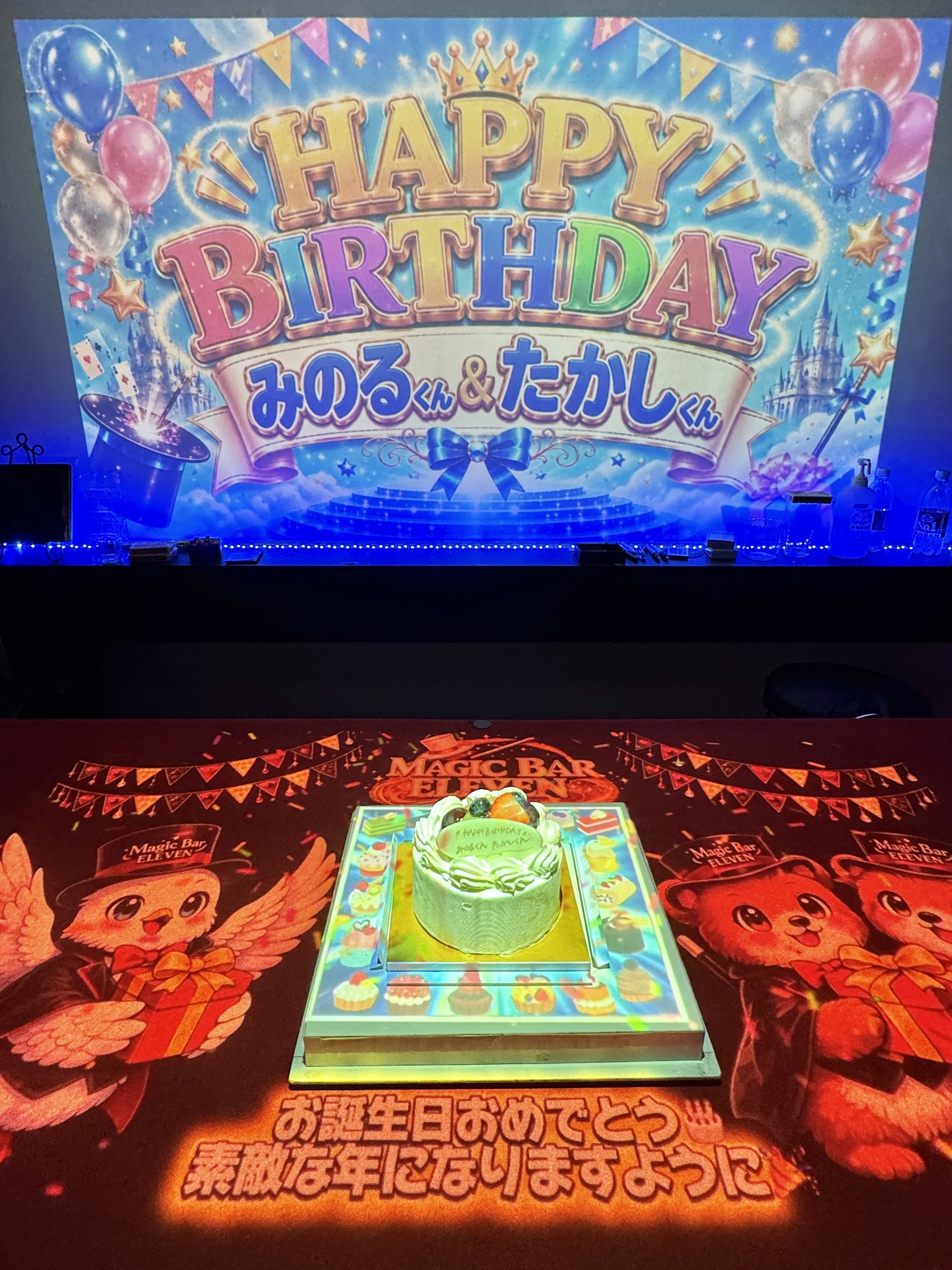 スクリーンとテーブルの映像でみのるくんとたかしくんを祝う大阪の誕生日サプライズ